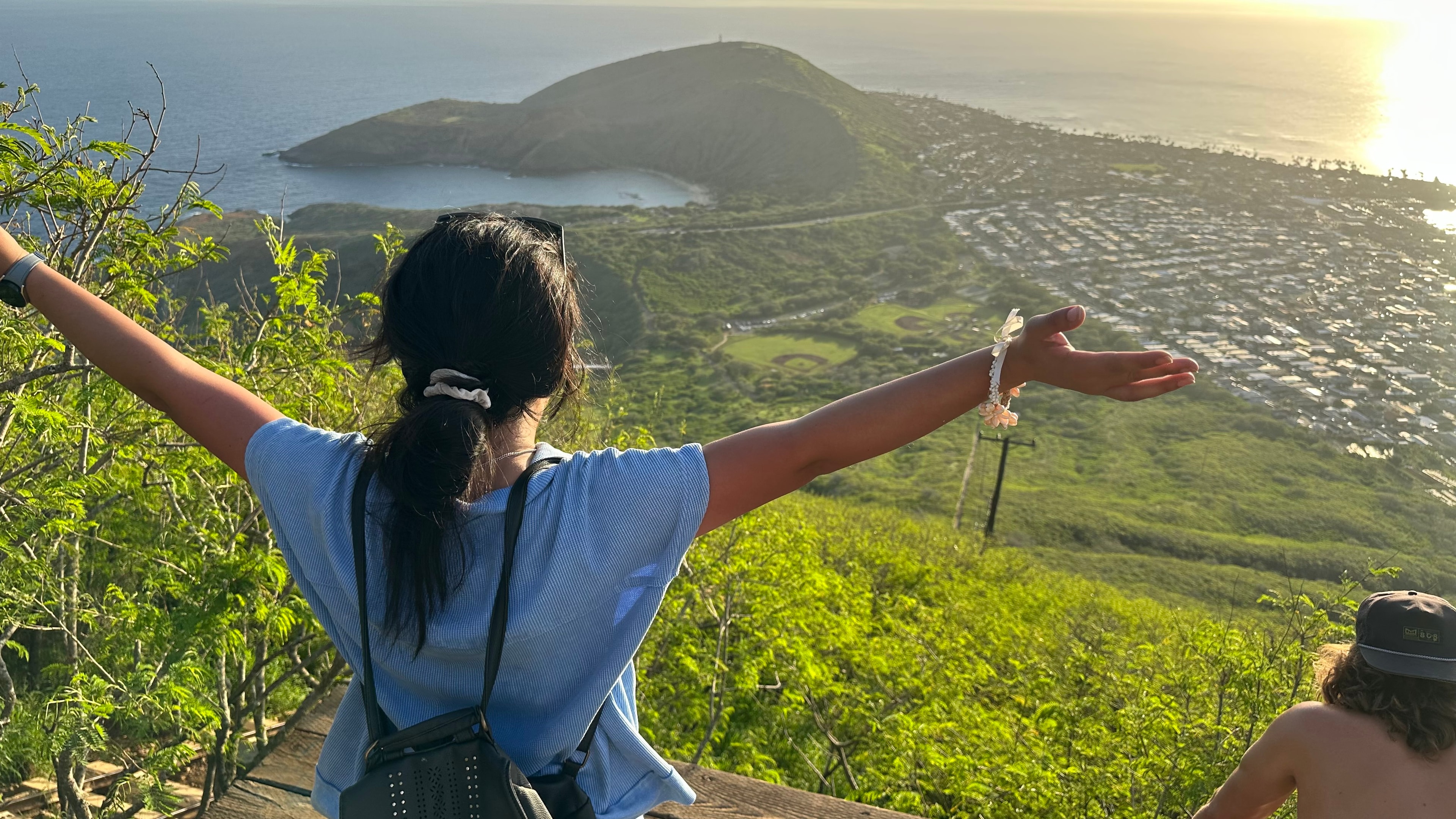 Priscilla at the top of Koko Head Crater Trail, arms wide open with the island below